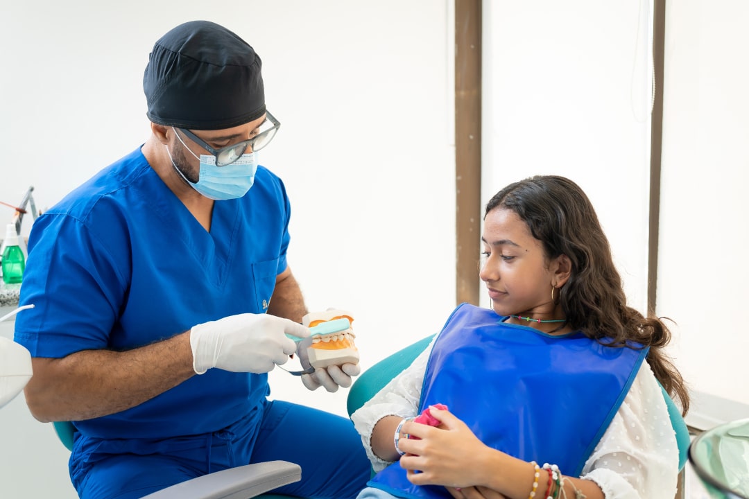 Odontólogo de Barrios Dental Care explicando el tratamiento a una paciente joven